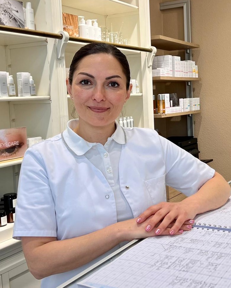 Ayse Eryilmaz im weißen Kittel an der Theke, hinter ihr Regale mit Pflegeprodukten